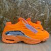 A pair of orange sneakers on a wooden table upclose against a rugged background