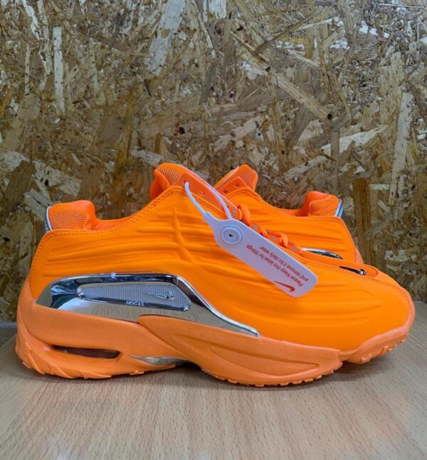 A pair of orange sneakers on a wooden table upclose against a rugged background